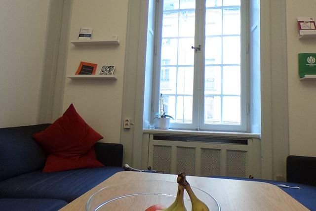 An office lounge with a sofa, cushions and a tall window