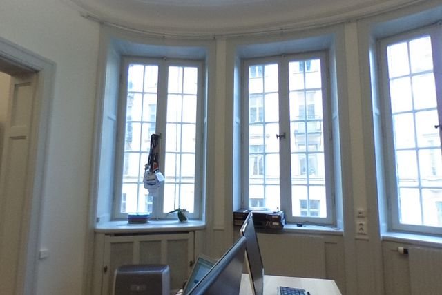 A working office interior with desks beneath tall windows