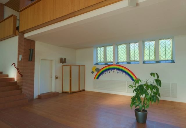 A bright multi-purpose hall with tall windows and a wooden floor