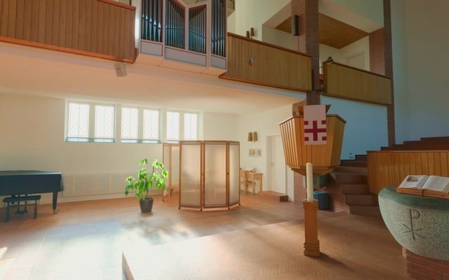 The entrance end of a light hall with wooden doors and a potted plant