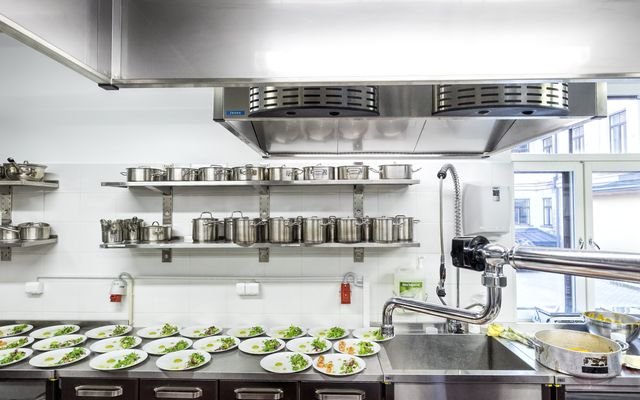 A stainless-steel professional kitchen with prepared plates on the counter