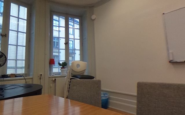 A meeting room with a long table and arched windows